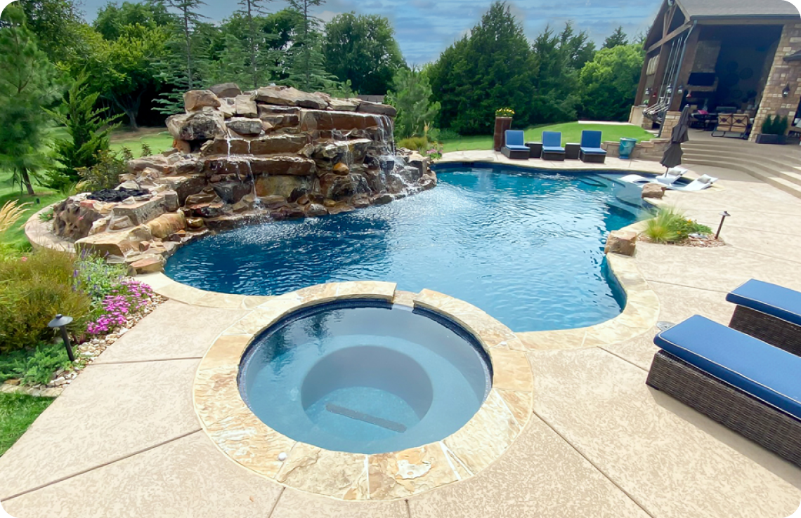 Free-form gunite pool with large, multi-tier waterfall and round spa.