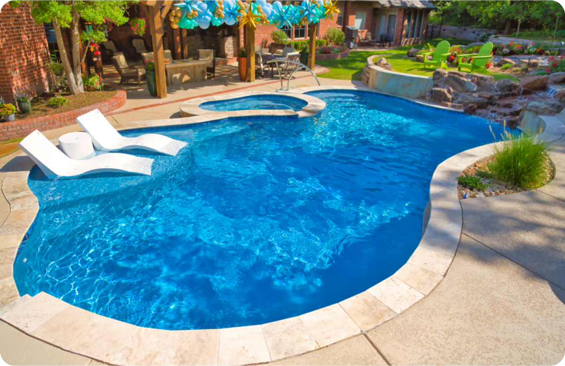 Free-form pool and spa with tanning ledge with chaise lounges.