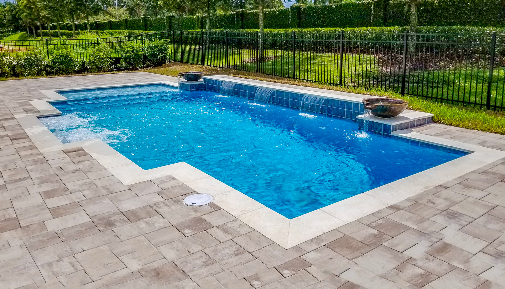 Modified rectangle-shaped pool with cascade water features. and two water bowls.