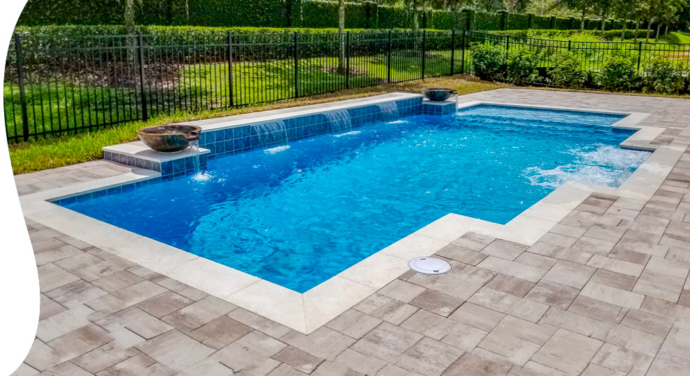Modified rectangular inground pool with water bowls and paver deck.