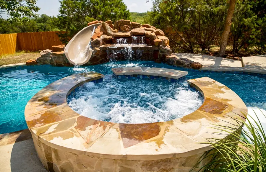 Pool and spa with flagstone exterior and rock waterfall with integrated pool slide.